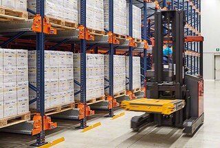 Operators ar autokrāvēju paceļ shuttle vagoneti un nogādā to uz norādīto uzglabāšanas kanālu