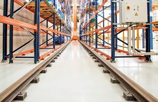 Trīsceļu automatizētais kraušanas celtnis pārvietojas gar eju pa apakšējo sliežu pāri